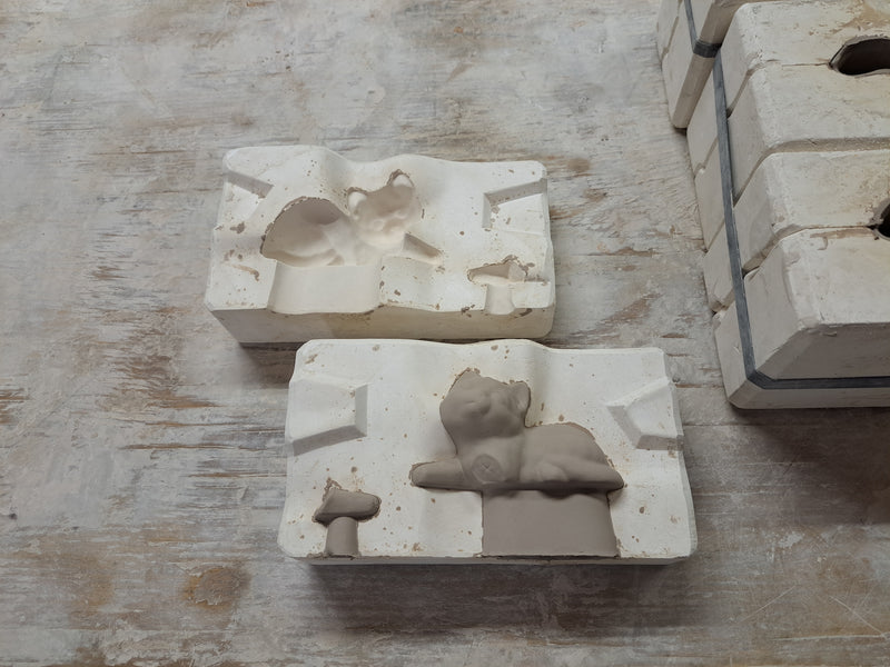 Small clay kittens in an opened mould after casting
