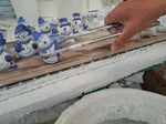 delftblue little snowman being dipped in glaze in delftpottery.