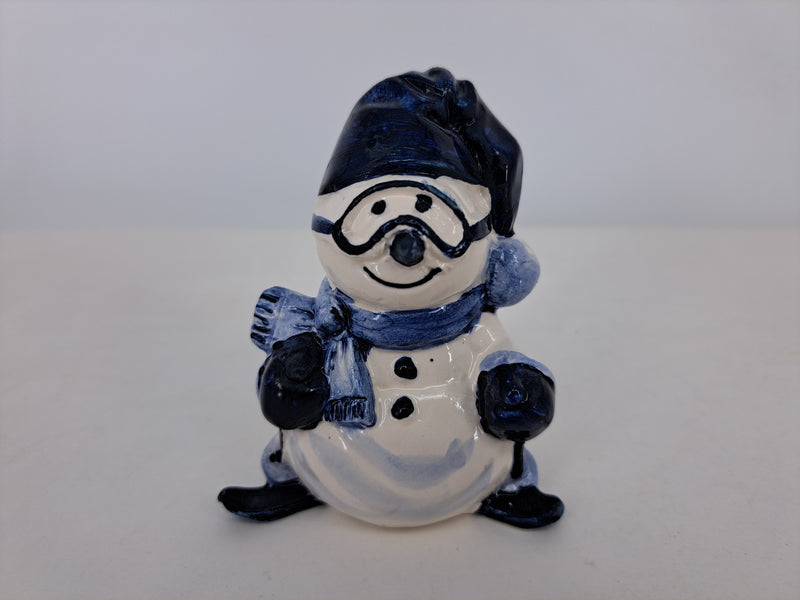 Delftblue snowman wearing a skiing outfit.