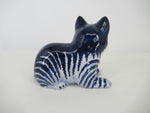 sitting ceramic blue striped cat, seen from its back.