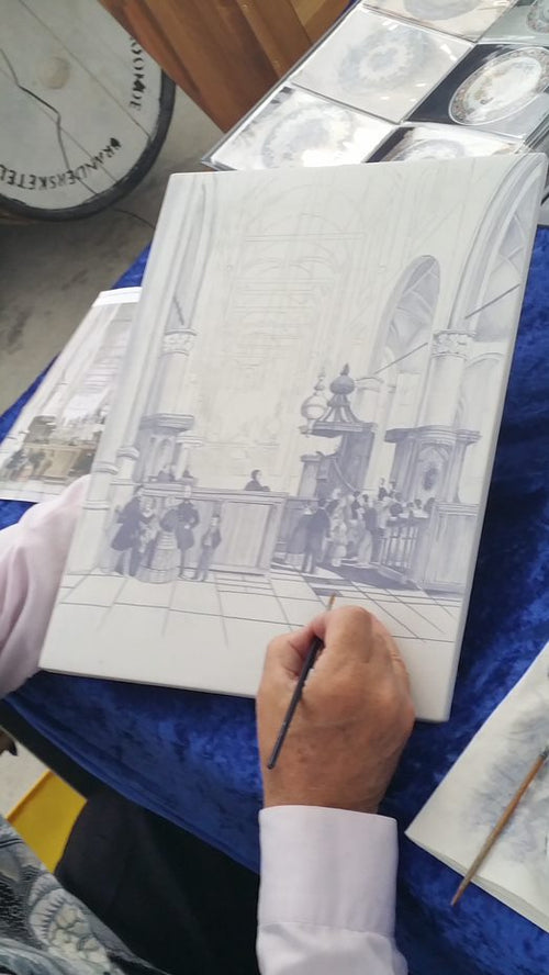Delftpainter painting a delft large plaque with a church interior.