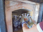 Delft tulipvase being taken from an old ceramic kiln with heat gloves.