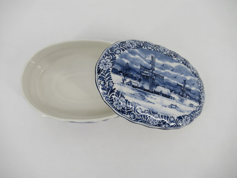 top view of an oval delftblue trinket with Dutch landscape painted on the lid.
