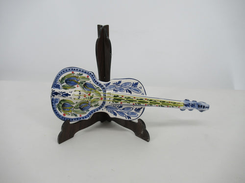 small ceramic violin in handpainted blue tulip design in a wooden stand.