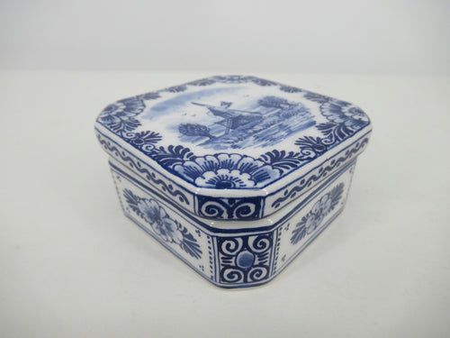 Detailled painted square delftbox with landscape and floral design.