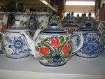  Teapot with a red tulip design on a warehouse shelf amongst other delftblue ceramic.