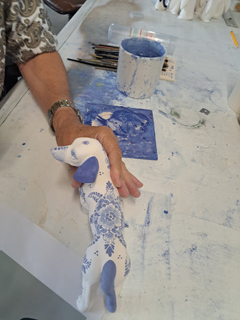 Painter showing the ceramic Daqchshund he just finished painting.