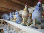 A row of large handpainted ceramic blue and multicolor roosters in our warehouse.