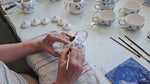 Our delftpainter Gonda is painting a small teapot in a floral Delft design.