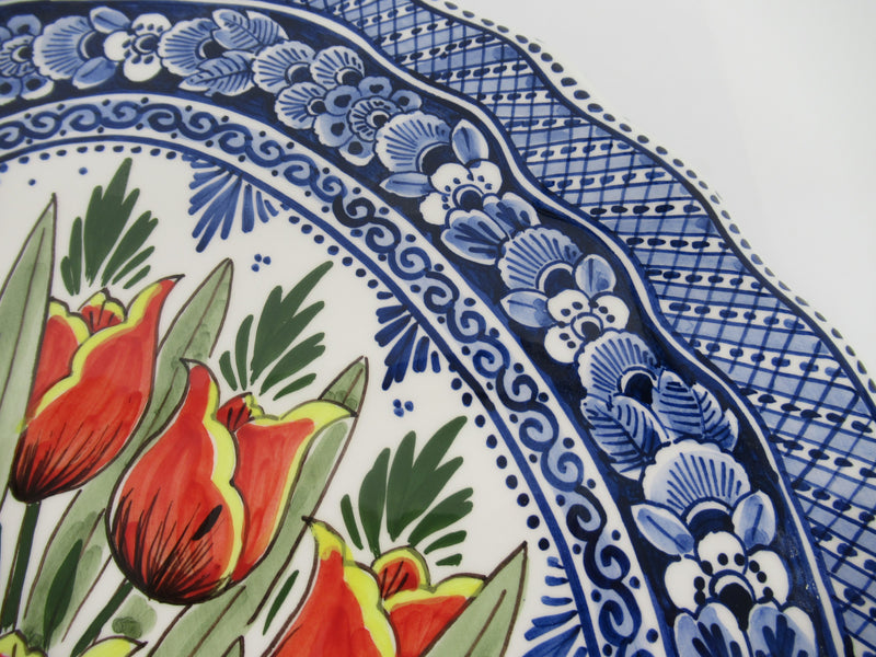 detail of a ceramic wall mural with a handpainted red tulip bouquet in a delftblue design