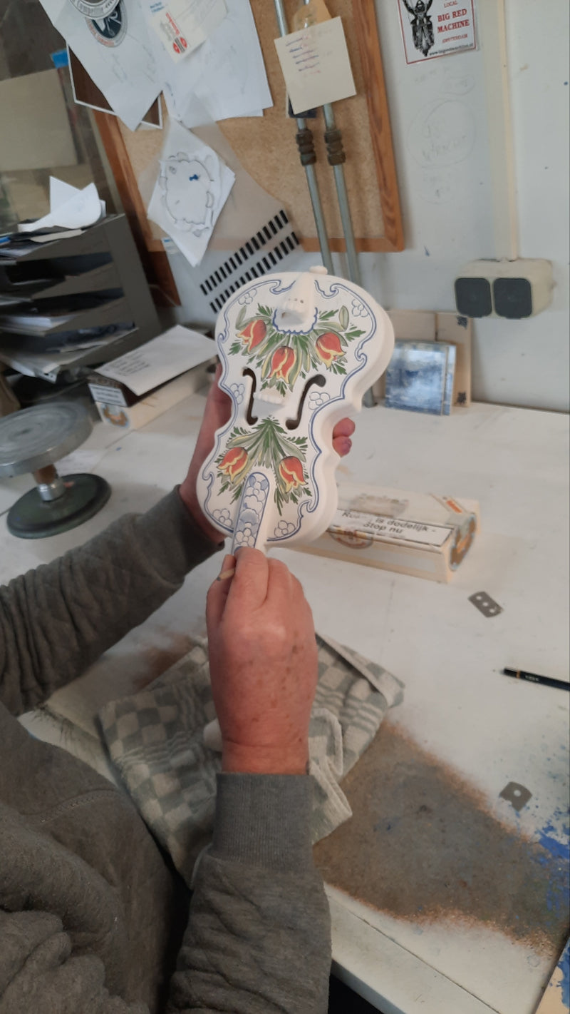 delftpainted Jan Born handpainting a ceramic delft violin with in red and tulip design