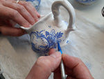 delftpainter is handpainting a delft tea cup